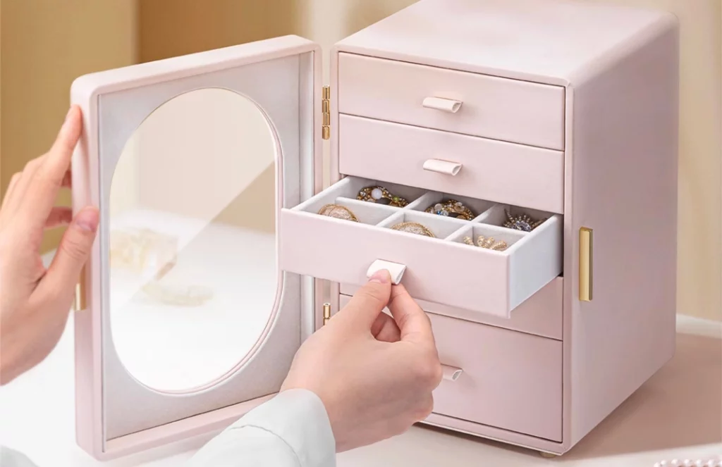 Jewelry box open showing necklace hooks behind glass door and drawers